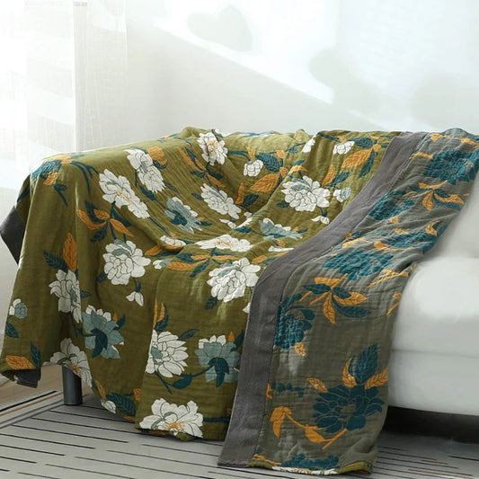 Folded olive green throw with charcoal border and floral accents, symbolising quiet elegance and balance
