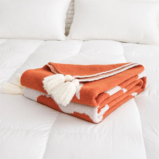 White and orange blanket featuring oversized floral prints; soft woven texture with large summer flowers, ideal for draping over a chair, sofa