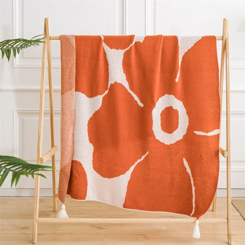White and orange blanket featuring oversized floral prints; soft woven texture with large summer flowers, ideal for draping over a chair, sofa or travel