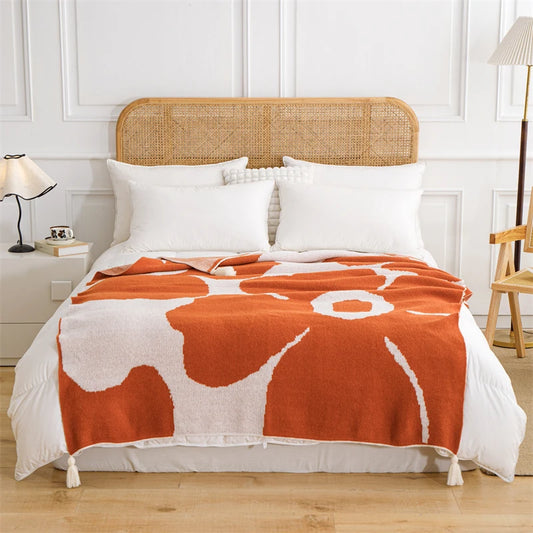 White and orange cotton blanket featuring oversized floral prints; soft woven texture with large summer flowers, ideal for draping over a chair, sofa, or at the foot of the bed.